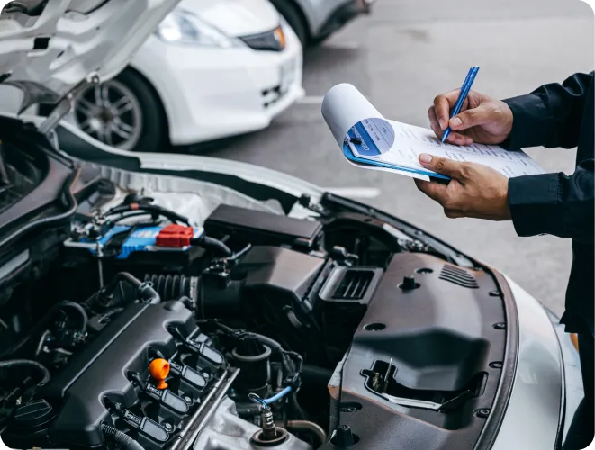 Person inspecting car engine with clipboard