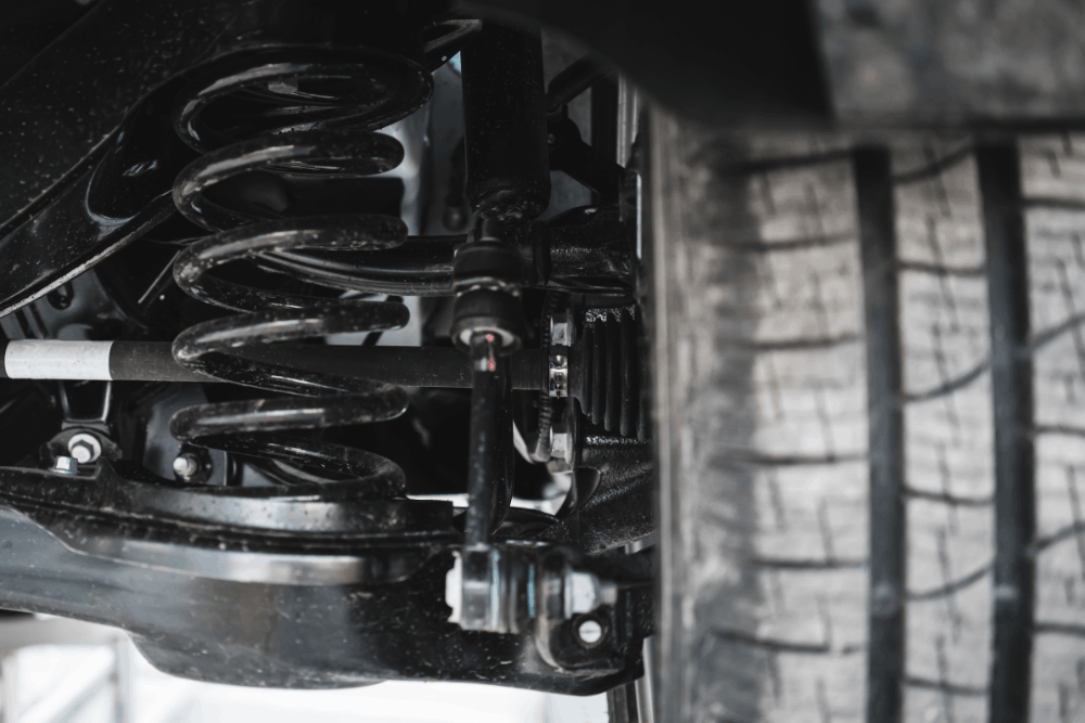 Image of a vehicle’s suspension system with coil spring and components, highlighting precise handling, improved ride comfort, and safe, stable driving performance.